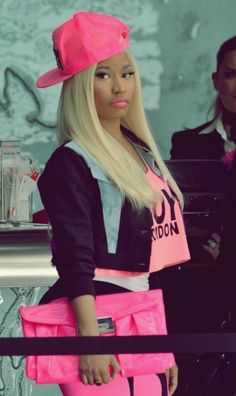 a woman with long blonde hair is holding a pink purse and posing for the camera