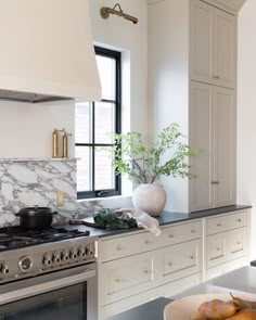 a kitchen with marble counter tops and white cabinets, along with a stove top oven