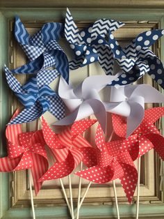 several red, white and blue pinwheels are on sticks in front of a wooden frame