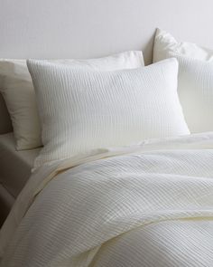 a bed with white sheets and pillows on it