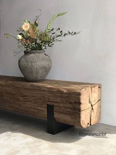 a vase with flowers sitting on top of a wooden bench