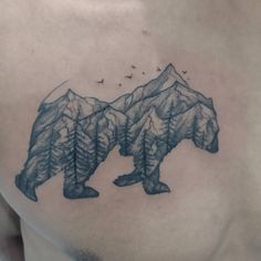 a man's chest with a bear and mountains tattoo on his left side shoulder