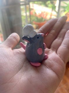 a hand holding a tiny toy mouse in it's palm