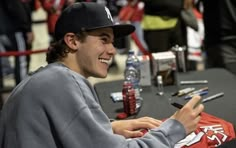 a young man sitting at a table signing autographs