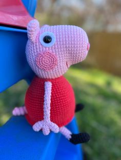 a crocheted pig sitting on top of a blue bench