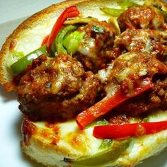 a meatball sandwich with peppers and onions on a white plate, ready to be eaten