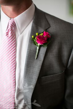 a man in a suit with a pink flower on his lapel