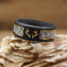 ABOUT THIS RING Material: Black Forged Carbon Fiber, 2 Gold Plated Strips, and a Natural Grain Antler Inlay with a Resin Coating. Color*/Finish: Black and Gold Engraving: Antlers with Gold Oil Width: 8mm *All Antler Rings are 100% Unique so color may vary slightly from image shown. Check out the information about our Antler Rings for more details! QUESTIONS ABOUT SIZING Go to our Ring Sizing Guide for details and important guidance. OTHER BENEFITS FOR YOU FREE ACTIVITY BAND with Purchase (a $55