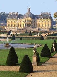 a large building with a fountain in front of it and lots of trees around it