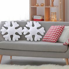 a grey couch with two snowflake pillows on it's armrests