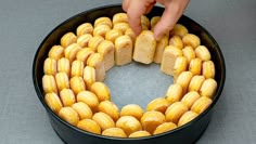 a person placing pieces of bread into a cake pan to make a heart - shaped wreath