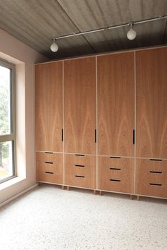 an empty room with wooden cabinets and windows