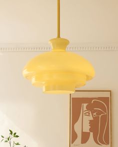 a yellow light hanging from the ceiling in a room with art on the wall and paintings