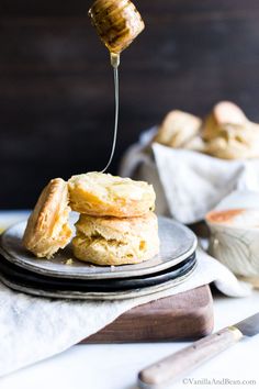 a stack of biscuits on a plate being drizzled with honey