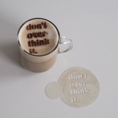 a cup of coffee with the words don't over this on it next to a coaster