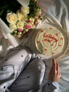 a woman laying on top of a bed with a cake