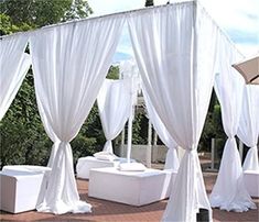 an outdoor bed with white drapes and pillows