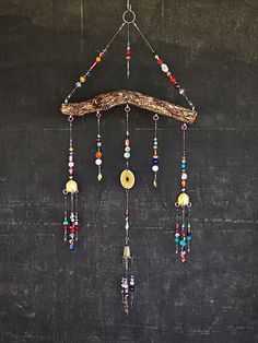 a wind chime hanging from a wooden branch with beads and other items on it