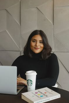 a woman sitting at a table with a laptop and coffee cup in front of her