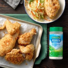 chicken wings and coleslaw are on a tray next to a bottle of ranch seasoning