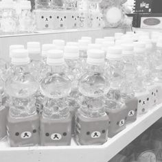 bottles of water are lined up on a shelf in a store, black and white