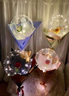 three vases with flowers and lights on them