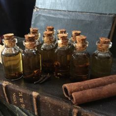 several small bottles filled with different types of liquids and cinnamons on top of an old book