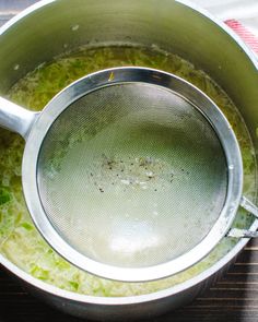 a pot filled with green liquid on top of a wooden table