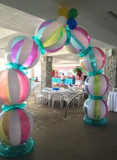 an arch made out of balloons in the middle of a room with tables and chairs