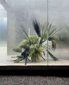 there is a vase with flowers in it on the floor next to a glass wall