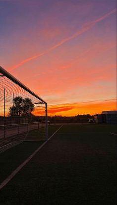 the sun is setting behind a soccer goal