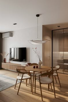 a living room with a table and chairs in front of a flat screen tv on the wall