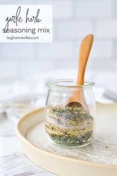 a wooden spoon sitting in a glass jar on top of a tray filled with spices