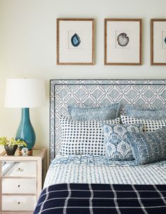 a bedroom with blue and white bedding, two pictures on the wall above it