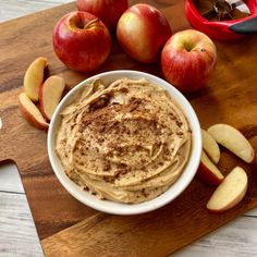 an apple and cinnamon dip in a white bowl on a cutting board next to sliced apples