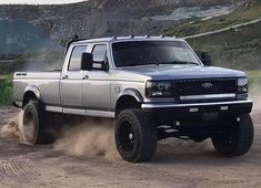 a silver truck driving down a dirt road