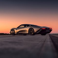 a silver sports car driving down the road at sunset