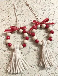 two red and white tasselled necklaces on a table with polka dot wallpaper