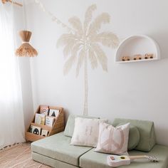 a living room with a green couch and a palm tree wall decal on the wall