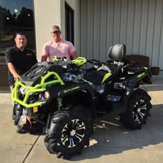 two men are standing next to an atv