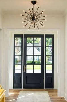 a black front door with two sidelights and a white rug on the wooden floor