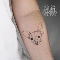 a small chihuahua tattoo on the left inner forearm and arm, with an inked dog's face