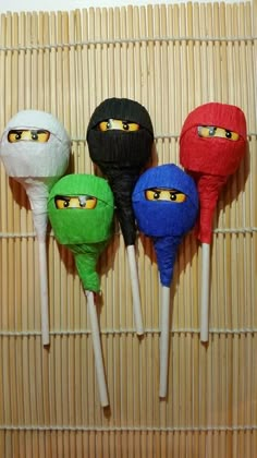 four different colored head shaped lollipops on top of a bamboo mat next to each other