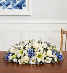 a bouquet of white and blue flowers sitting on top of a wooden table