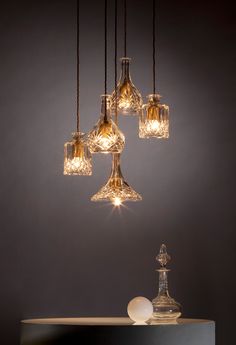 an assortment of wine glasses hanging from a chandelier over a table with lights on it