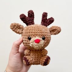 a hand holding a small crocheted stuffed animal in the shape of a reindeer