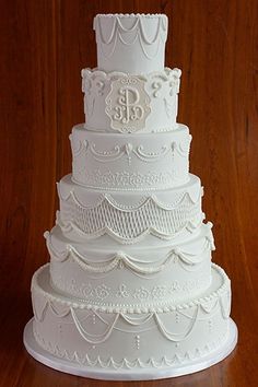 a large white wedding cake sitting on top of a wooden table