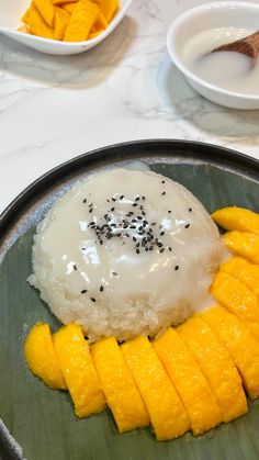 a plate with rice, mango slices and sauce on it next to bowls of fruit