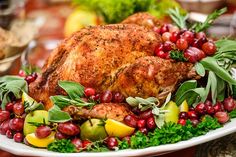 a roasted turkey with cranberries, apples, and herbs on a platter