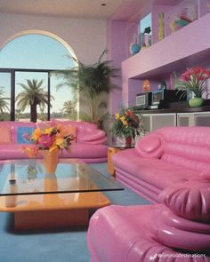 a living room filled with pink furniture and lots of windows overlooking the ocean in front of palm trees